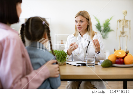 Mature pediatrician receives female patient in modern clinic. 114746113