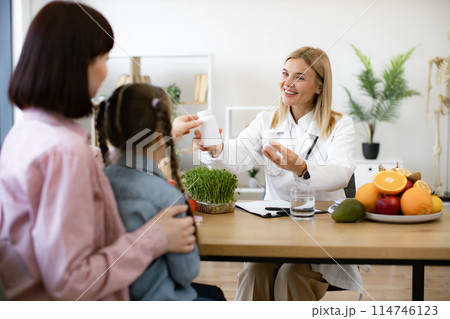 Happy pretty female nutritionist holding bottles with pills. Happy pretty female nutritionist holding bottles with pills. 114746123