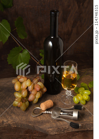 Still life with glass of white wine and grapes on vintage wooden background.. Still life with glass of white wine and grapes on vintage wooden background.. 114746315