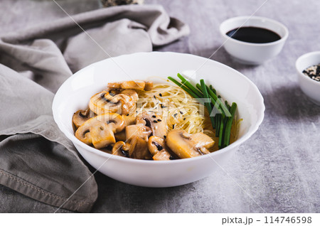 Funchose rice noodles with mushrooms and green onions in a bowl on the table 114746598