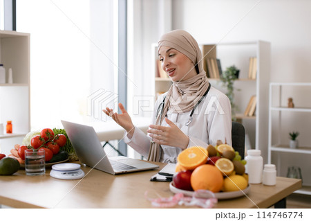 Muslim female making video call via wireless device at doctor's workplace. Muslim female making video call via wireless device at doctor's workplace. 114746774