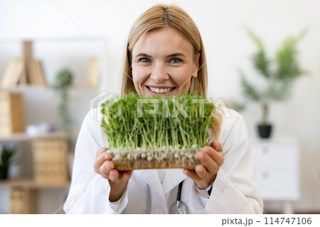 Charming Caucasian woman in doctor's coat with microgreens. 114747106