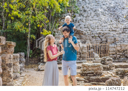 Mom, dad and baby tourists at Coba, Mexico. Ancient mayan city in Mexico. Coba is an archaeological area and a famous landmark of Yucatan Peninsula. Cloudy sky over a pyramid in Mexico 114747212