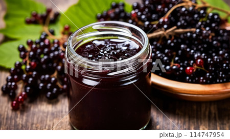 Elderberry jam nestled in a glass jar on a wooden table Elderberry jam nestled in a glass jar on a wooden table 114747954