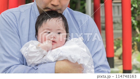 【父親に抱かれお宮参りの赤ちゃんと赤い鳥居】 【父親に抱かれお宮参りの赤ちゃんと赤い鳥居】 114748163