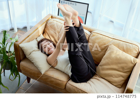ソファに寝そべって足を上げる女性 114748775