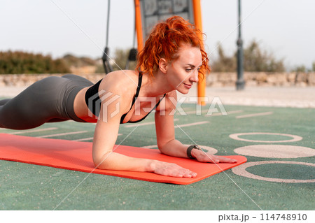 Redhead woman doing plank exercise on mat at 114748910
