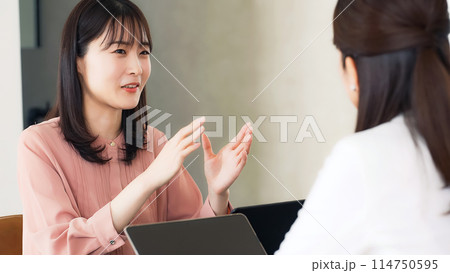 オフィスで会話するカジュアルウェアの女性グループ 114750595