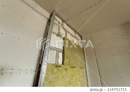 Metal frame for future walls with drywall plates insulated with rock wool and fiberglass insulation staff for cold barrier. Comfortable warm home, economy, construction and renovation concept. Metal frame for future walls with drywall plates insulated with rock wool and fiberglass insulation staff for cold barrier. Comfortable warm home, economy, construction and renovation concept. 114751715