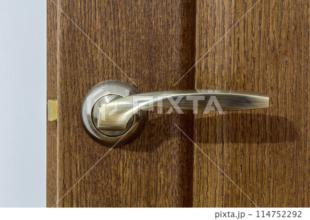 Modern, contemporary satin metal handle on a wooden door close-up. 114752292