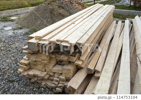 Stack of natural brown uneven rough wooden boards on building site. Industrial timber for carpentry, building, repairing and furniture, lumber material for roofing construction. Stack of natural brown uneven rough wooden boards on building site. Industrial timber for carpentry, building, repairing and furniture, lumber material for roofing construction. 114753104