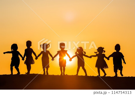 Kids holding hands against sunset 114754313