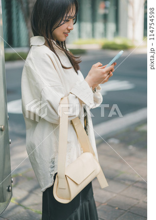 休日に街に出かけた若い女性がスマホを操作するシーン 114754598