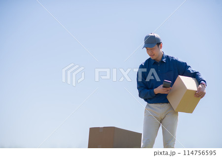 荷物を確認する配達員 114756595