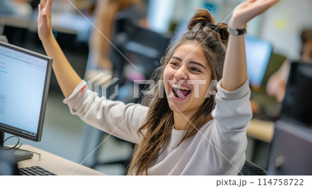 パソコンの前で喜ぶ女子 Happy girl in front of PC 114758722