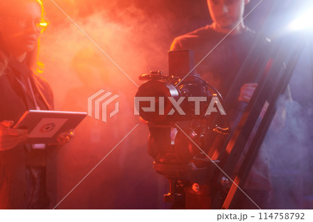 Background image of pro video camera equipment backstage in red neon light, copy space 114758792