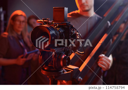 Closeup of cameraman operating video camera on rig in studio with red neon lights copy space 114758794