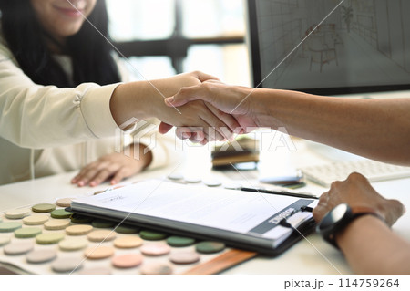 Smiling female client shaking hands with Interior designer after signing agreement 114759264