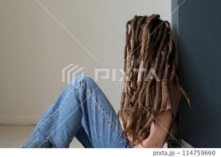 Side view portrait of unrecognizable woman with long dreadlocks sitting on floor minimal copy space Side view portrait of unrecognizable woman with long dreadlocks sitting on floor minimal copy space 114759660