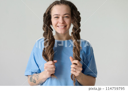 Minimal portrait of carefree Caucasian woman holding long dreadlocks in braids and smiling at camera copy space 114759795