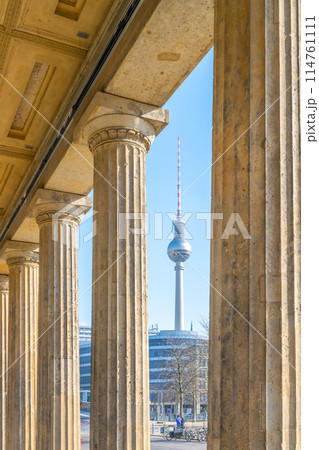 The Berlin TV Tower stands tall, framed by the classical columns of a nearby historical building on a clear day. Berlin, Germany The Berlin TV Tower stands tall, framed by the classical columns of a nearby historical building on a clear day. Berlin, Germany 114761111