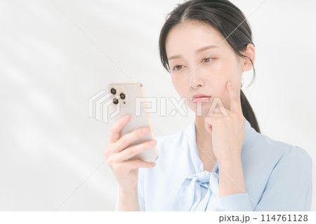 スマホを操作する考える表情の女性 スマホを操作する考える表情の女性 114761128