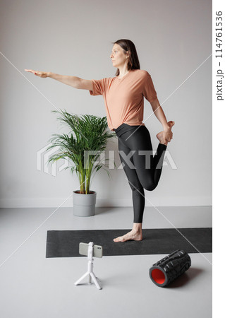 young Caucasian woman does sports online, stretches, practices yoga, meditation in gym 114761536