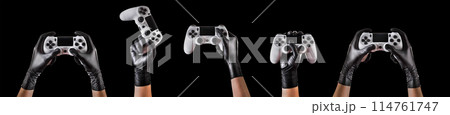 Hand in black gloves holding console gamepad isolated on black background 114761747