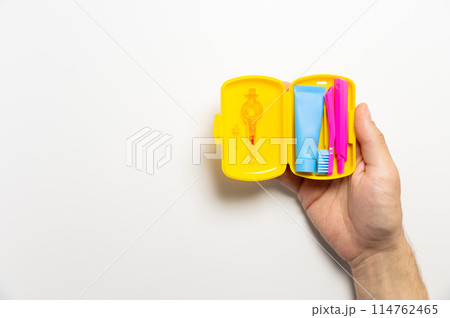 Dental hygiene and oral care products in a yellow travel cosmetic bag on a white background with copy space in a man's hand. Flat lay, top view composition Dental hygiene and oral care products in a yellow travel cosmetic bag on a white background with copy space in a man's hand. Flat lay, top view composition 114762465
