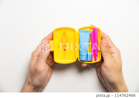 Dental hygiene and oral care products in a yellow travel cosmetic bag on a white background with copy space in a man's hand. Flat lay, top view composition Dental hygiene and oral care products in a yellow travel cosmetic bag on a white background with copy space in a man's hand. Flat lay, top view composition 114762466