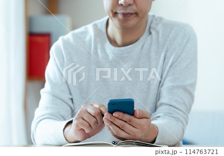 スマホと手帳をチェックするミドル男性 114763721