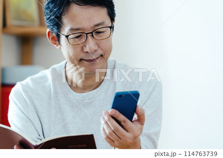 スマホと手帳をチェックするミドル男性 スマホと手帳をチェックするミドル男性 114763739