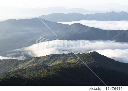 Early morning landscape. Colorful sunrise on a foggy day over mountains and a forest. Early morning landscape. Colorful sunrise on a foggy day over mountains and a forest. 114764164