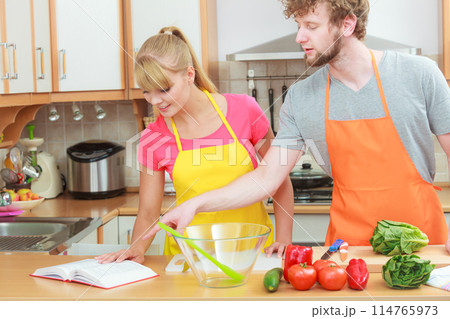 Couple cooking in kitchen reading cookbook 114765973