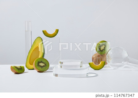 Two podiums in round shaped stacked on each other, displayed with few slices of avocado and kiwi. Concept laboratory tests and research natural extract making cosmetics 114767347
