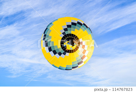 Colorful hot air balloon flying over blue sky with white clouds 114767823
