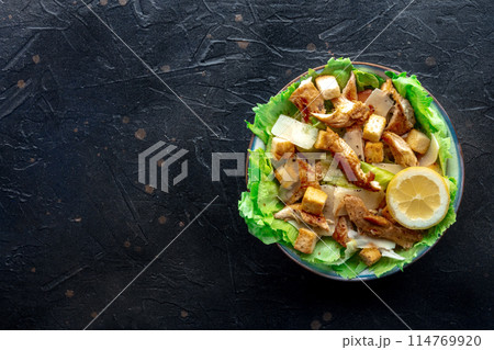 Caesar salad with chicken breast, lettuce, croutons, and a lemon Caesar salad with chicken breast, lettuce, croutons, and a lemon 114769920