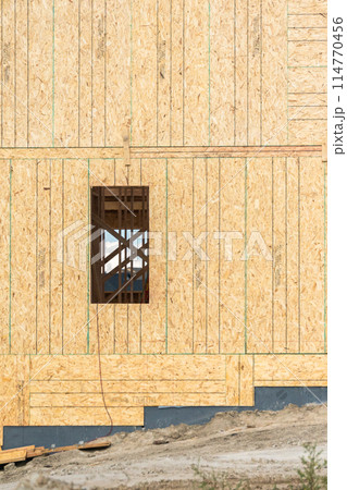 An ongoing construction site in the suburbs, featuring the framing stage of a single-family house. 114770456