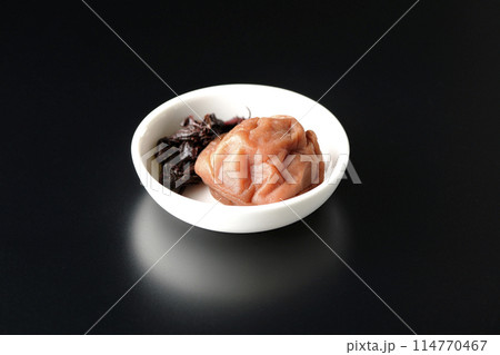 小皿に盛られた赤紫蘇と梅干しを黒背景で撮影 小皿に盛られた赤紫蘇と梅干しを黒背景で撮影 114770467