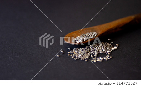 Group of chia grains on a wooden spoon.dark background.Still life. Group of chia grains on a wooden spoon.dark background.Still life. 114771527