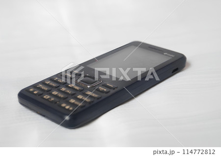 A black flip phone is laying on a white surface A black flip phone is laying on a white surface 114772812