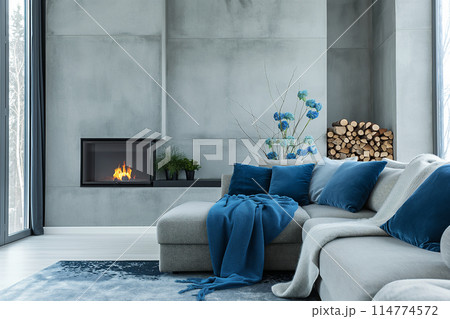 暖炉が埋め込まれたRC壁を背景に、グレーのソファセットが配置されたモダンなリビングルームのインテリア 114774572