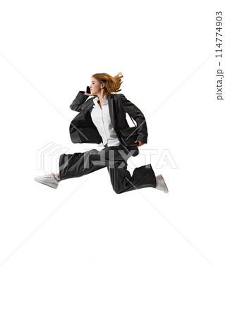 Businesswoman in formal attire having call in mid-air against white studio background. Flexibility and grace in business. Businesswoman in formal attire having call in mid-air against white studio background. Flexibility and grace in business. 114774903