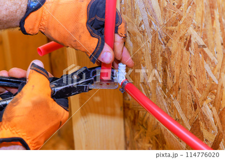 An installation connection to PVC plastic water pipes is completed by plumber 114776020
