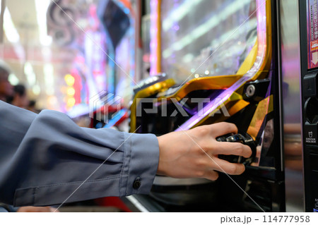 パチンコ台を遊戯する男性 114777958