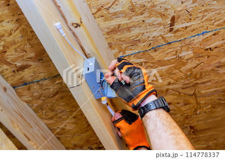 Electrician installing recessed ceiling lights with power junction box in new home Electrician installing recessed ceiling lights with power junction box in new home 114778337