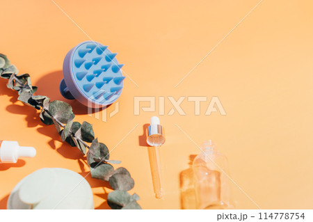 Massagers for scalp and glass jars with serum on a yellow background 114778754