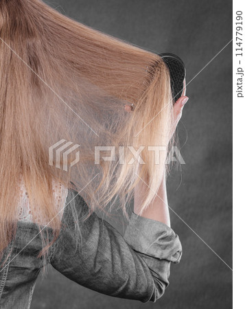 Blonde woman combing her hair. 114779190