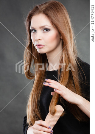 Long haired girl combing her beauty hair. 114779415