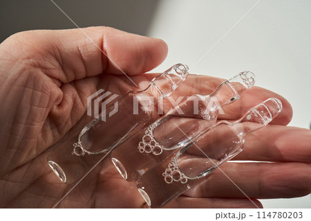 Ampoules for injection with medicines on a pink background in hand. Ampoules for injection with medicines on a pink background in hand. 114780203